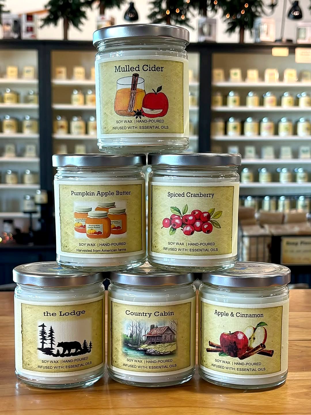 Fall candles stacked on the shop counter: Mulled Cider, Pumpkin Apple Butter, Spiced Cranberry, The Lodge, Country Cabin, and Apple & Cinnamon